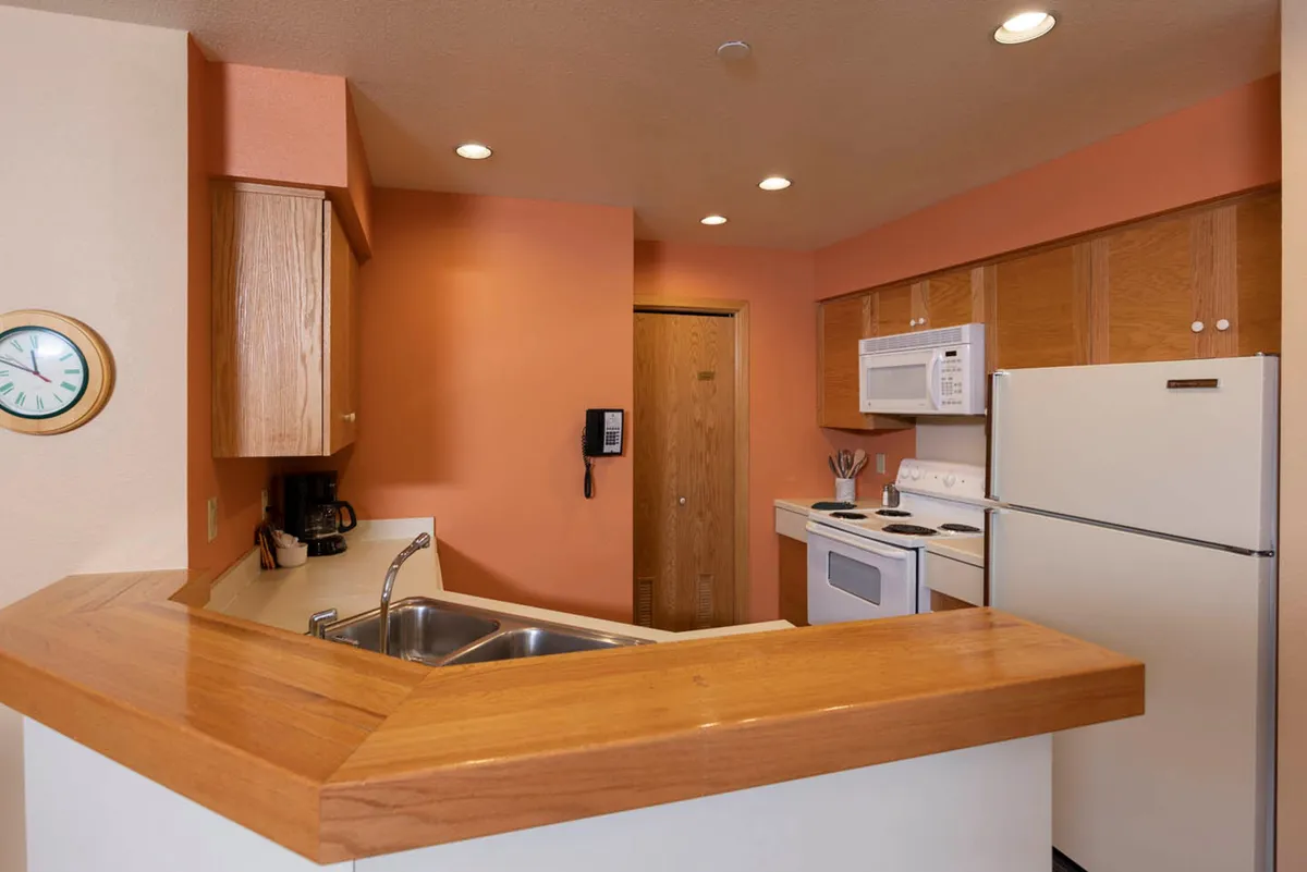 Here, the focus is on the kitchen counter, complete with a sink, sleek appliances, and plenty of workspace. The scene is set for cooking and socializing, with a warm, homey ambiance. The image subtly conveys the readiness of the space for preparing holiday meals or sharing recipes with loved ones, reinforcing the communal and practical aspects of the kitchen.