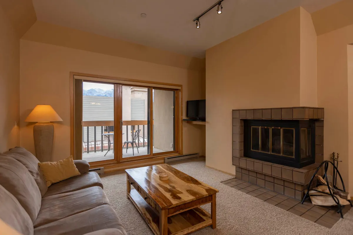 A cozy living area with a welcoming fireplace and a large window offering sunset views. The comfortable space is ideal for relaxing or socializing after a day spent exploring the mountains and resort amenities.